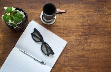 Not defteri, kalem, gözlük ve kahve fincanı ile Ofis ahşap masa. Düz yatıyordu