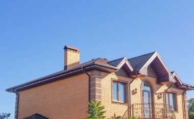 Berrak mavi gökyüzü altında güzel dövme ile Modern tuğla baca. Balkon, pencere ve yağmur olukları ile modern tuğla evin cephe