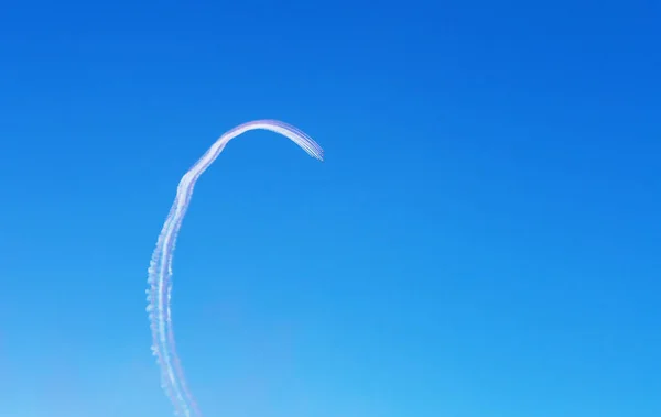 Los aviones dejan rastros curvos en el cielo azul claro. Vista desde abajo — Foto de Stock