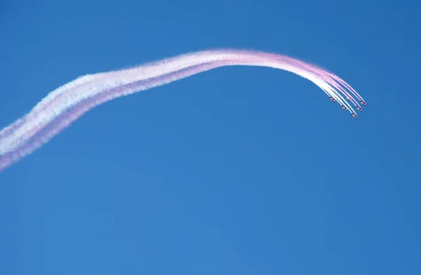 Αεροροματική ομάδα που πετάει σε σχηματισμό και αφήνει λευκό ροζ ίχνος καπνού στο γαλάζιο του ουρανού — Φωτογραφία Αρχείου