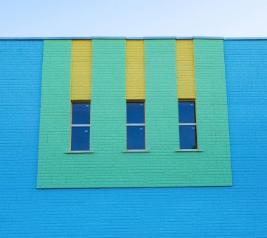 Üç dar dikey pencere yeşil ve sarı renk mavi tuğla duvar
