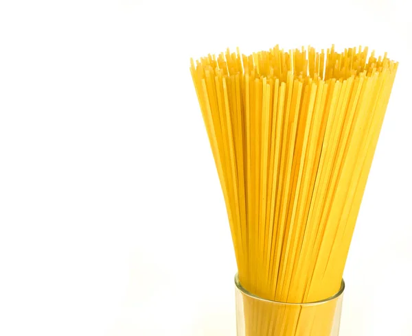 Close up of bunch of uncooked spaghetti in a glass isolated on white background with copy space — Stock Photo, Image