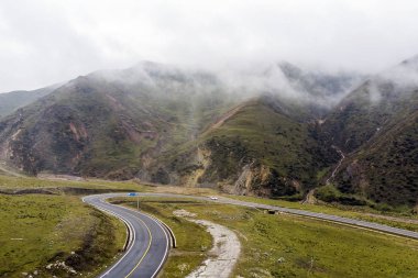Bulutlar, yeşil tepelerin ve beyaz araba ve yeni asfalt yol virajlı dağ yollarında. Valley nemli iklim.