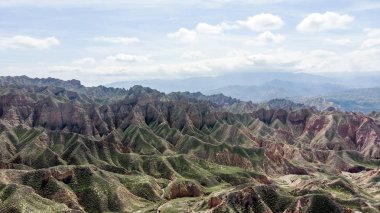 Zhangye, Sünen bölge, Gansu Eyaleti, Çin Binggou Danxia Kanyon ılık hava görünümünü. Geopark keskin sivri tepeler. Alçak bulutlar ve mavi gökyüzü güneşli bir günde.