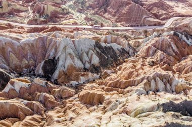 Üstten Görünüm gökkuşağı dağlar jeolojik park. Çizgili Zhangye Danxia ılık jeolojik Park Gansu Eyaleti, Çin. Turist otobüsleri güneşli bir günde bir vadide bir yolda resmini uçak.
