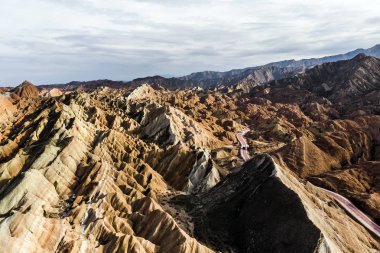 Üstten Görünüm gökkuşağı dağlar jeolojik park. Çizgili Zhangye Danxia ılık jeolojik Park Gansu Eyaleti, Çin. Turist otobüsleri güneşli bir günde bir vadide bir yolda resmini uçak.