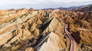 Üstten Görünüm gökkuşağı dağlar jeolojik park. Çizgili Zhangye Danxia ılık jeolojik Park Gansu Eyaleti, Çin. Yol bir vadide güneşli bir resmini uçak.