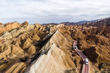 Üstten Görünüm gökkuşağı dağlar jeolojik park. Çizgili Zhangye Danxia ılık jeolojik Park Gansu Eyaleti, Çin. Turist otobüsleri güneşli bir günde bir vadide bir yolda resmini uçak.