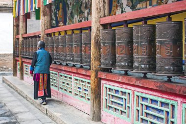 Silindir bir Budist tapınağında dua metal ciddi. Bir dua Tibet bir manastırda dini unsurları dönen. Kadın Kumbum tapınakta dua ediyor.