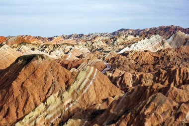 Gökkuşağı dağlar jeolojik Park tepesinde. Çizgili Zhangye Danxia ılık jeolojik Park Gansu Eyaleti, Çin. Güneşli bir günde keskin tepeler ve Valley Road.
