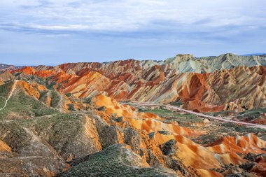 Gökkuşağı dağlar jeolojik Park şaşırtıcı görünümü. Çizgili Zhangye Danxia ılık jeolojik Park Gansu Eyaleti, Çin. Güneşli bir günde keskin tepeler ve yol bir vadide.