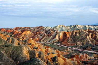 Gökkuşağı dağlar jeolojik Park serin bakış. Çizgili Zhangye Danxia ılık jeolojik Park Gansu Eyaleti, Çin. Güneşli bir günde keskin tepeler ve yol bir vadide.