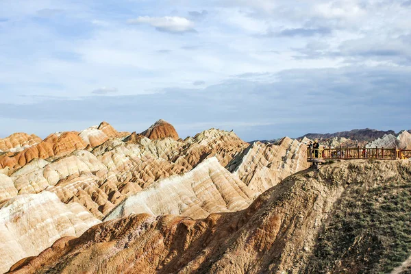 Chinese Tourists are in the Viewing Platform and Top of Rainbow Mountains Geological Park. Stripy Zhangye Danxia Landform Geological Park in Gansu Province, China. People are on the Observation Deck, Sharp Peaks and Valley on a Sunny Day.