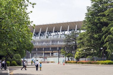 İnsanlar Tokyo'da Yeni Ulusal Stadyumu şantiye etrafında bir kare üzerinde yürüyor.