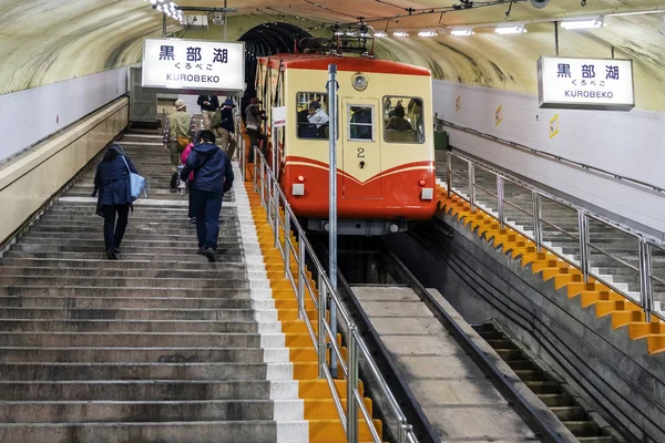 Подземный трамвай на крутом склоне, и люди забираются в тоннель — стоковое фото