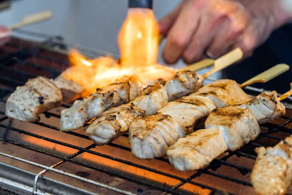 A Man Is Cooking Fresh Tuna Sticks On A Grill.