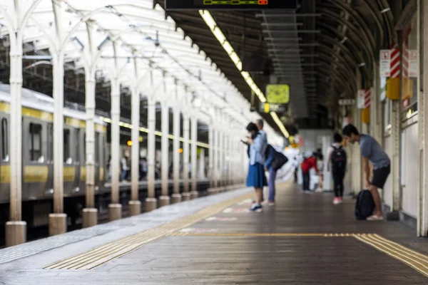 Persone offuscate sono sulla piattaforma in una stazione ferroviaria — Foto Stock