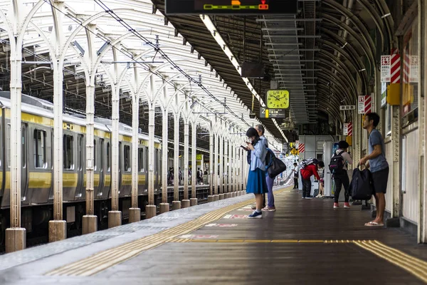 Le persone sono sulla piattaforma in una stazione ferroviaria . — Foto Stock