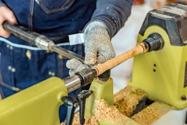Marangoz ahşap sopayı oyuyor. Dönen tahta tekerlek makinesi. Yuvarlak bir detay oluşturuyorum. Joiner atölyede el yapımı dekorasyon yapmak için metal araç kullanıyor.