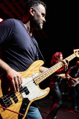 Kafkasyalı adam sahnede bandoyla performans sergiliyor. Yakışıklı Erkek Konserde Bass Gitarında Çalıyor.
