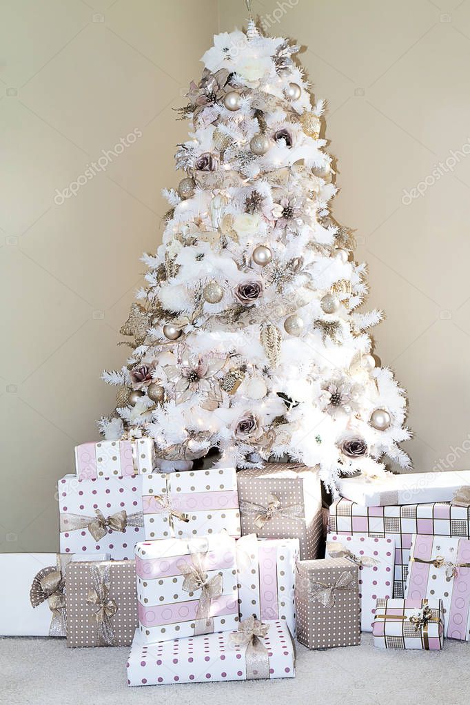 Dreamy white Christmas tree in living room of home decorated in popular colors blush pink, golds and whites with matching presents under the tree.