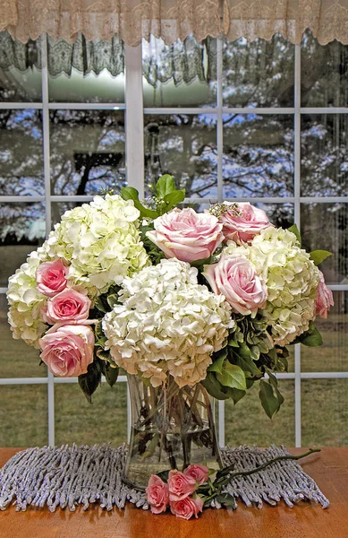 ガラスの花瓶に美しい花のアレンジメントは 白いアジサイや柔らかいピンクのバラでいっぱい 周りの家の台所のテーブルに表示されます — ストック写真