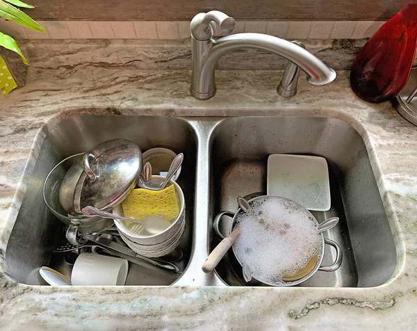 Dirty dishes in kitchen\'s double stainless steel sink.