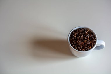 Kalın duvarlı seramik bardak ağzına kadar taze kavrulmuş kahve çekirdekleri ile dolu.