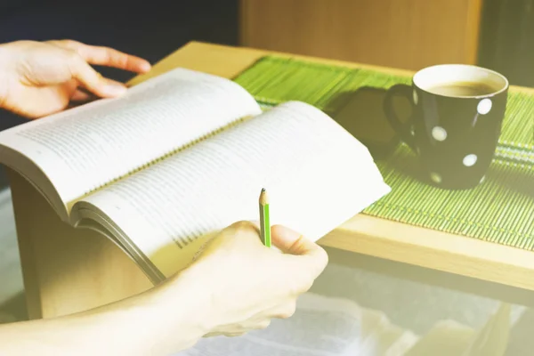 本とノートをとり ホット コーヒーとテーブルの上の携帯電話を楽しむのための鉛筆を保持している若い女性 — ストック写真