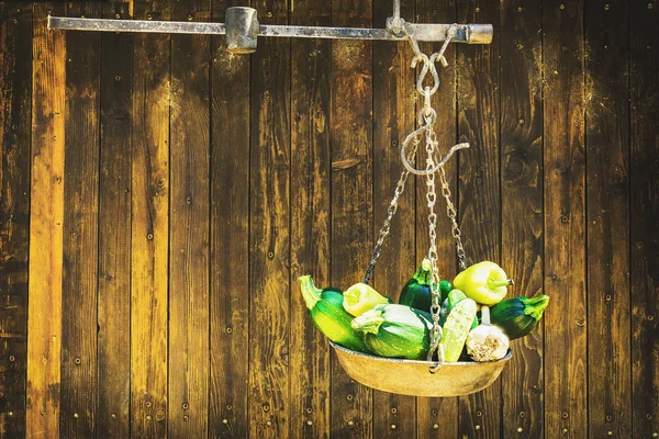 green marrow squash (Zucchini) and garlic hanging in metal beam scale in front of wooden rustic door, space for text and various design