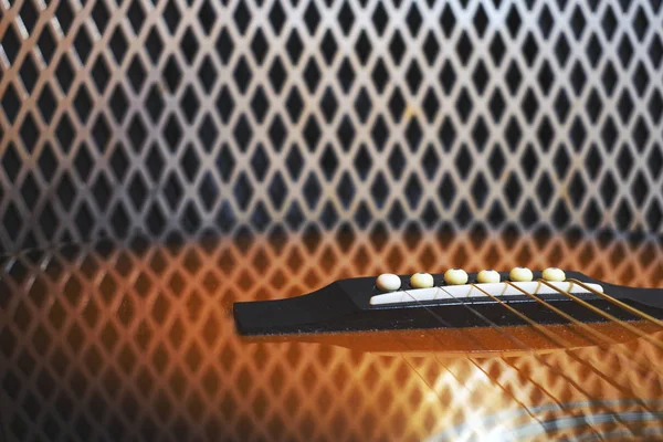 Acoustic guitar resonator box reflecting the metal grill of an electric guitar amplifier. Musical background