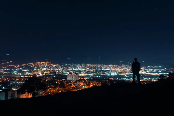 Gece boyunca büyük şehir. Tepenin üstünde şehrin üzerinde duran, gece fotoğrafçılığı yapmak fotoğrafçı siluet.