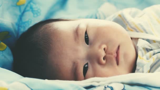接近一个两个月可爱的亚洲婴儿放松和看相机的脸 婴儿躺在床上 健康儿童概念 老式胶片过滤效果 电影风格的颜色 — 图库视频影像