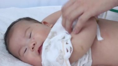Profesyonel çocuk doktoru muayene bebek. Çocuğun göğüs kalp atışlarını kontrol için dinlemek için bir stetoskop kullanarak doktor. Hasta yatağının hastanede yatan iki ay bebek Asyalı kız.