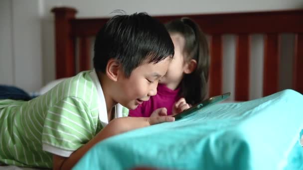 아시아 어린이 디지털 태블릿을 여입니다 그녀의 패드에 경향이 침대에 귀여운 — 비디오