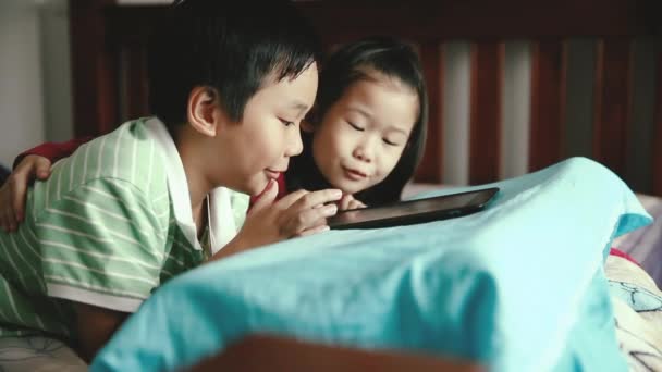 アジアの子供たちはデジタル タブレットを使用します 笑みを浮かべて 彼女の弟を応援して喜んで姉妹 かわいい男の子が興奮してタッチパッド上のゲームをプレイします ビンテージ フィルム フィルター効果と映画のトーン — ストック動画