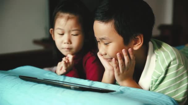 アジアの子供たちはデジタル タブレットを見てします 中国の少年 彼女の弟を抱き締める妹に焦点を当てます ラーニング技術や兄弟関係概念を使用します 映画のトーン — ストック動画