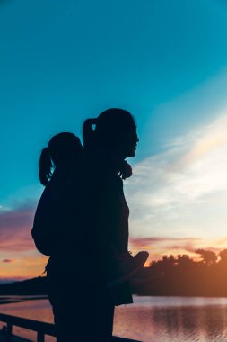 Anne vererek Atçılık kızına sabah, rahat ruh silüeti. Pastel renkli gökyüzü gündoğumu, serenity arka plan. Mutlu bir aile birlikte vakit. Tatil seyahat.