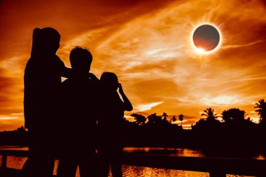 Amazing scientific natural phenomenon. The Moon covering the Sun. Silhouette of mother and children looking at total solar eclipse with diamond ring effect on sky. Happy family spending time together. clipart