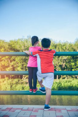 Arkadan görünüm. Asya çocuk birbirlerine sarılma. Nazikçe kardeş kardeşi ile egzersiz sonrası, açık havada üzerinde yaz günü rahatlatıcı. Kavramı için iyi sağlıklı egzersiz hakkında. Vintage film filtre efekti.