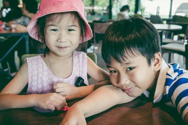 かわいいアジアの女の子は コーヒー ショップで彼女の兄と一緒に完璧な笑顔を浮かべてします 幸せな家族の時間を一緒に過ごす 愛する兄弟の接合します ビンテージ フィルム効果 — ストック写真