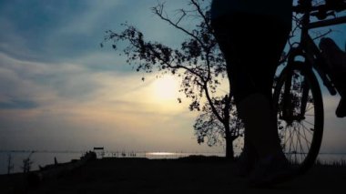 Egzersiz germe, sahil, Bisiklet ile yürüyen bisikletçi kadın silüeti. Kadın motorcu deniz gündoğumu sabah, rahat ruh hali üzerinde güzel doğada sağlıklı aktif yaşam tarzı zevk.