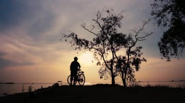Egzersiz germe, sahil, Bisiklet ile yürüyen bisikletçi kadın silüeti. Kadın motorcu deniz gündoğumu sabah, rahat ruh hali üzerinde güzel doğada sağlıklı aktif yaşam tarzı zevk.