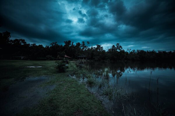 Moonlight shines behind a cloudy at night over tranquil lake
