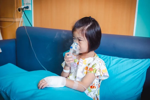 悲しいアジアの子供は喘息の治療のためのマスク蒸気吸入器を保持します 蒸気噴霧器を通して呼吸する 手持ちの生理食静脈内静脈内 中に入院した病気の少女 — ストック写真