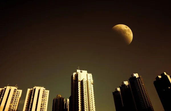 Paisaje urbano por la noche y cielo oscuro con media luna — Foto de Stock