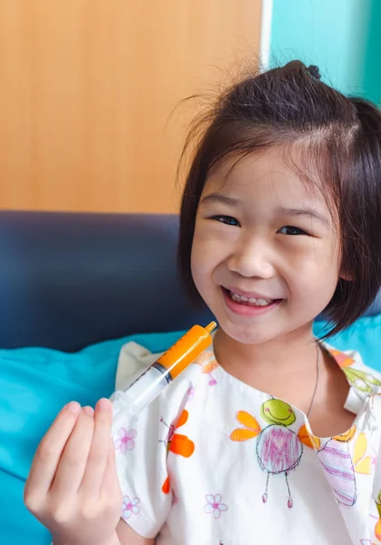 Krankheit asiatisches Kind lächelt glücklich, während es ins Krankenhaus eingeliefert wird und nimmt Medikamentensirup. — Stockfoto