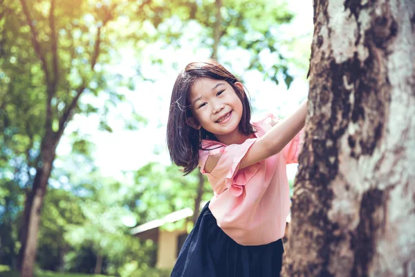 Cute Little Asian Girl pod wielkim drzewem na zewnątrz w parku. — Zdjęcie stockowe