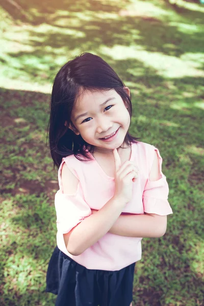 Retrato de um sorrindo pouco ásia menina no verde grama no o pa — Fotografia de Stock