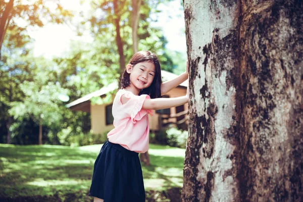 Schattige kleine Aziatische meisje onder grote boom buiten in het Park. — Stockfoto